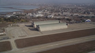 AXSF11_052 - 5K aerial stock footage tilt from a parked jet to reveal and approach Hangar Two and Three, Moffett Field, Mountain View, California