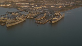 AXSF14_001 - 5K aerial stock footage flyby base and reveal USS Hornet and ships at Naval Air Station Alameda, California, sunset