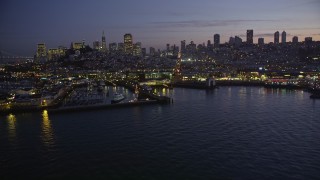 AXSF14_088 - 5K aerial stock footage flyby Fisherman's Wharf, downtown skyline in the background, reveal Pier 39, San Francisco, California, twilight