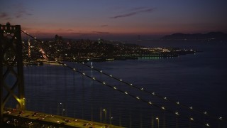AXSF14_114 - 5K aerial stock footage of flying over Bay Bridge while focusing on Coit Tower, North Beach, San Francisco, California, twilight