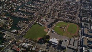 AXSF15_002 - 5K aerial stock footage of a reverse view of suburban neighborhoods and baseball fields, Alameda, California