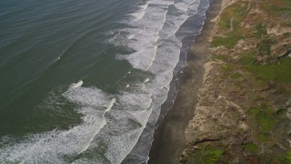 AXSF15_033 - 5K aerial stock footage fly away from waves rolling toward beach and cliffs in the Lakeshore District, San Francisco, California