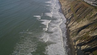 AXSF15_035 - 5K aerial stock footage of flying away from ocean waves rolling toward coastal cliffs, Daly City, California