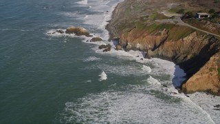 AXSF15_037 - 5K aerial stock footage fly away from waves rolling into coastal cliffs and rock formations, Daly City, California