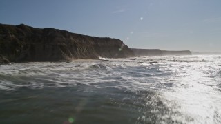 AXSF15_060 - 5K aerial stock footage of flying low over the ocean near cliffs, Half Moon Bay, California