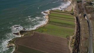 AXSF15_085 - 5K aerial stock footage of a reverse view of crop fields by Highway 1, train tracks, Davenport, California