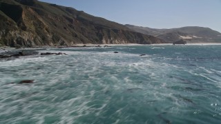 AXSF16_076 - Aerial stock footage of 5K aerial video of flying over the ocean, tilt up to reveal coastal cliffs, Big Sur, California