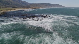 AXSF16_091 - 5K aerial stock footage tilt from ocean, reveal seagulls flying over rocks along coast, Big Sur, California