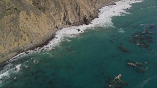 AXSF16_107 - 5K aerial stock footage bird's eye view of kelp near waves rolling toward coastal cliffs, Big Sur, California
