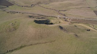 AXSF16_147 - 5K aerial stock footage of a reverse view of grassy hills, reveal country road in San Luis Obispo County, California