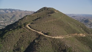 AXSF16_155 - 5K aerial stock footage tilt up slope of a mountain with dirt roads and fly over it to reveal San Luis Obispo, California