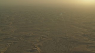 CAP_001_001 - HD stock footage aerial video of a desert road through sand dunes at sunrise in Al Gharbia, Abu Dhabi, UAE