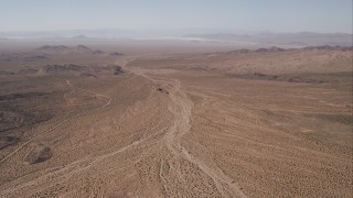 CAP_005_022 - HD stock footage aerial video of a dirt road by an arid valley, Mojave Desert, California