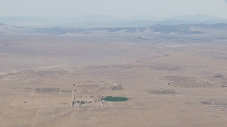 CAP_006_020 - HD stock footage aerial video approach a crop field and a Mojave Desert monastery in Newberry Springs, California