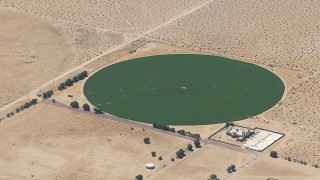 CAP_006_023 - HD stock footage aerial video of a reverse view of a crop field beside a Mojave Desert monastery in Newberry Springs, California