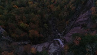 CAP_014_017 - 2.7K stock footage aerial video a bird's eye view of forest under a clifftop waterfall at sunset, Chimney Rock, North Carolina