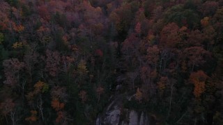 CAP_014_018 - 2.7K stock footage aerial video a reverse view of forest, reveal a clifftop waterfall at sunset, Chimney Rock, North Carolina