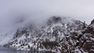 CAP_015_002 - 4K stock footage aerial video of panning across snowy mountain slopes beside lake in Inyo National Forest, California