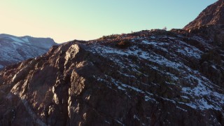 CAP_015_031 - 4K stock footage aerial video ascend by rocky slope with snow at sunset, Inyo National Forest, California