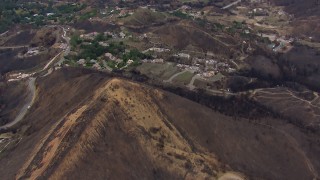CAP_018_019 - HD stock footage aerial video of flying over a mountain scarred by fire to approach destroyed homes, Malibu, California