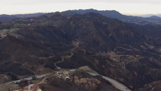 CAP_018_027 - HD stock footage aerial video reverse view of hillside homes destroyed by fire by scorched mountains, Malibu, California