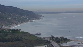 CAP_018_051 - HD stock footage aerial video of flying toward Malibu Pier and oceanfront homes with a view of DTLA skyline at sunset, Malibu, California