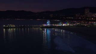CAP_018_112 - HD stock footage aerial video approach Ferris wheel and rides at night, Santa Monica Pier, California