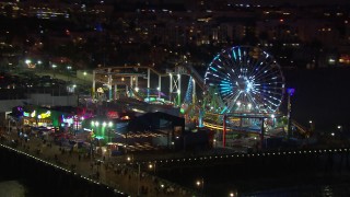 CAP_018_116 - HD stock footage aerial video orbit the Ferris wheel and rides at night, Santa Monica Pier, California
