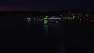 CAP_018_117 - HD stock footage aerial video a slow approach to the Ferris wheel and rides at nighttime, Santa Monica Pier, California
