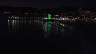 CAP_018_118 - HD stock footage aerial video approach the Ferris wheel and rides at nighttime, Santa Monica Pier, California