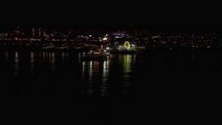 CAP_018_121 - HD stock footage aerial video flying over the ocean toward the Ferris wheel and rides at nighttime, Santa Monica Pier, California