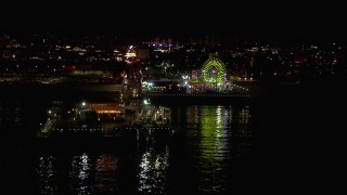 CAP_018_122 - HD stock footage aerial video flying over the ocean to approach the Ferris wheel and rides at nighttime, Santa Monica Pier, California