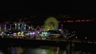 CAP_018_124 - HD stock footage aerial video of a reverse view of the Ferris wheel and rides at nighttime, Santa Monica Pier, California