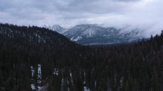 CAP_019_011 - 4K stock footage aerial video of snowy mountains, descend by evergreen forest, Inyo National Forest, California