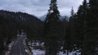 CAP_019_012 - 4K stock footage aerial video of snowy mountains, descend by road through evergreen forest, Inyo National Forest, California