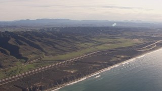 CAP_021_043 - HD stock footage aerial video of a reverse view of I-5 between mountains and coastal cliffs, San Clemente, California