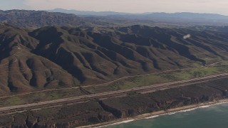 CAP_021_044 - HD stock footage aerial video of panning across I-5 between mountains and coastal cliffs, San Clemente, California