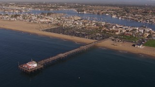 CAP_021_077 - HD stock footage aerial video approach and orbit pier by the beach and coastal neighborhoods, Newport Beach, California
