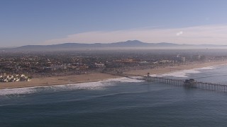 CAP_021_083 - HD stock footage aerial video of flying by a pier and the beach in Huntington Beach, California