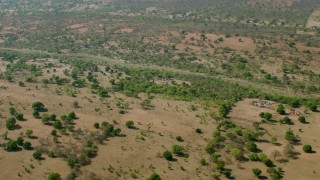 CAP_026_013 - HD stock footage aerial video of approaching a village across a dry river in open savanna, Zimbabwe