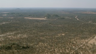 CAP_026_061 - HD stock footage aerial video of flying over savanna toward hills beside fields, Zimbabwe