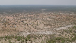 CAP_026_070 - HD stock footage aerial video of flying over a village with the savanna in the background, Zimbabwe