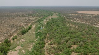 CAP_026_074 - HD stock footage aerial video of following a nearly dried up river past trees in savanna, Zimbabwe