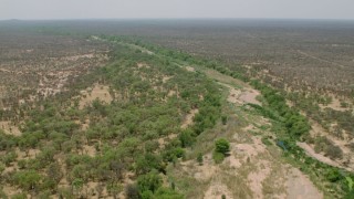 CAP_026_075 - HD stock footage aerial video of flying over a dry riverbed past trees in savanna, Zimbabwe