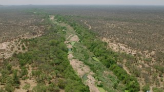 CAP_026_076 - HD stock footage aerial video of following a dry riverbed past trees in savanna, Zimbabwe