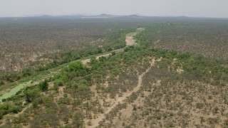 CAP_026_077 - HD stock footage aerial video of flying by a dry riverbed and trees in savanna, Zimbabwe