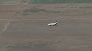 CBAX01_007 - HD aerial stock footage of tracking Cessna 340 in flight over farmland, hazy, Perris, California