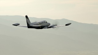 CBAX01_016 - HD aerial stock footage of tracking Cessna 340 over hills on hazy day; Perris, California