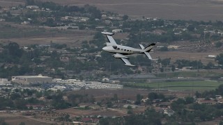 CBAX01_020 - HD aerial stock footage of tracking Cessna 340 entering frame, flying over rural town, Perris, California