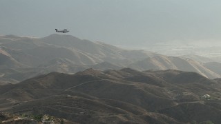 CBAX01_021 - HD aerial stock footage of flying by hazy hills, revealing Cessna 340 entering frame, Perris, California